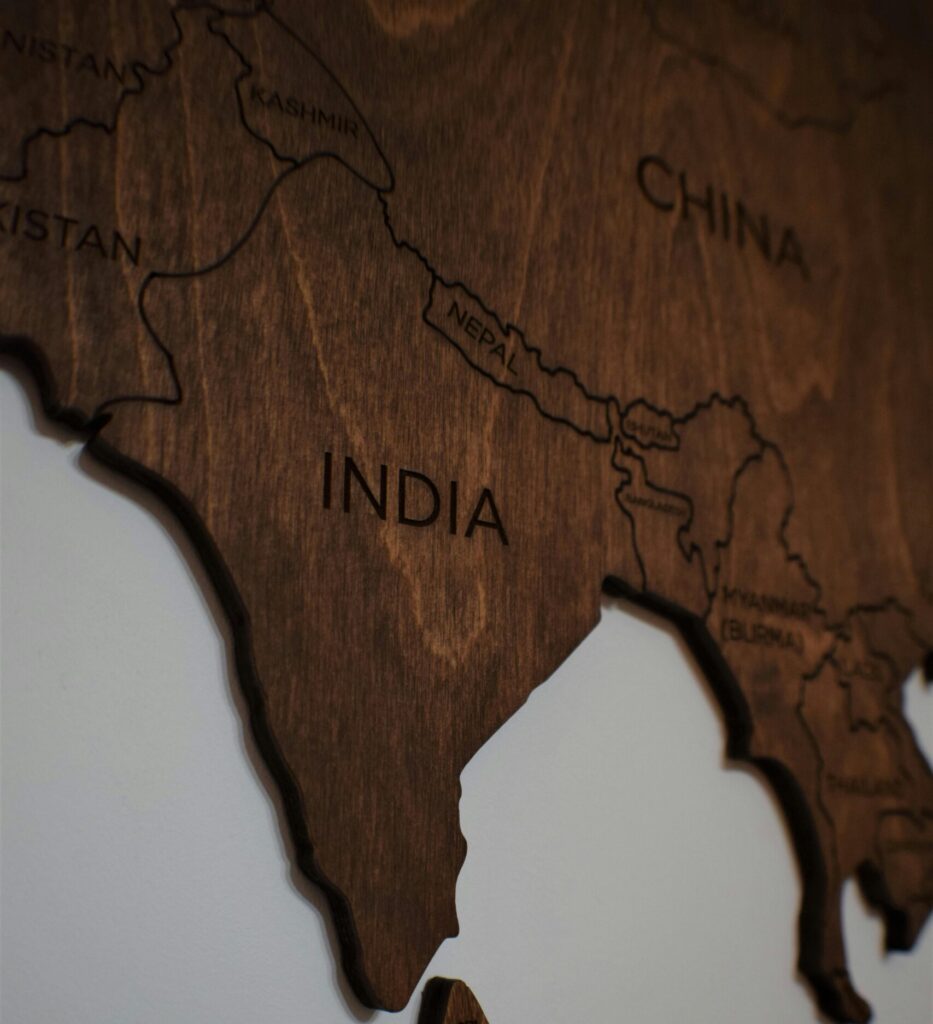 Close-up of a wooden carved map showing countries in South Asia on a white wall.